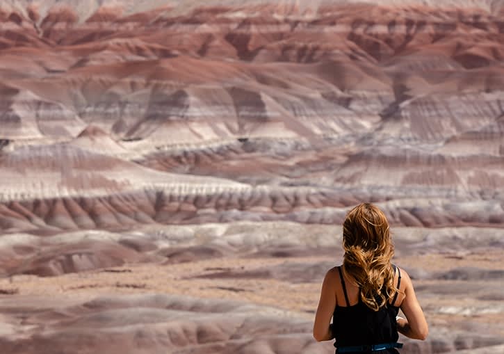 A woman admires the red and white sandstones of the Little Painted Desert County park with her back to the camera.
