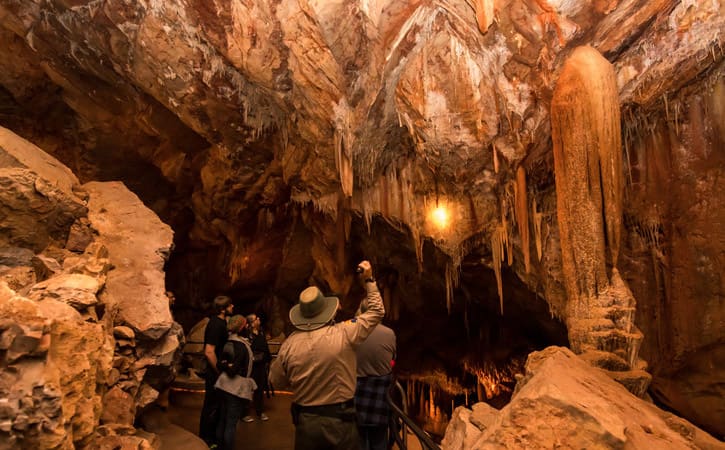 A tour guide holds a flashlight to illuminate centuries-old speleothems inside a cavern
