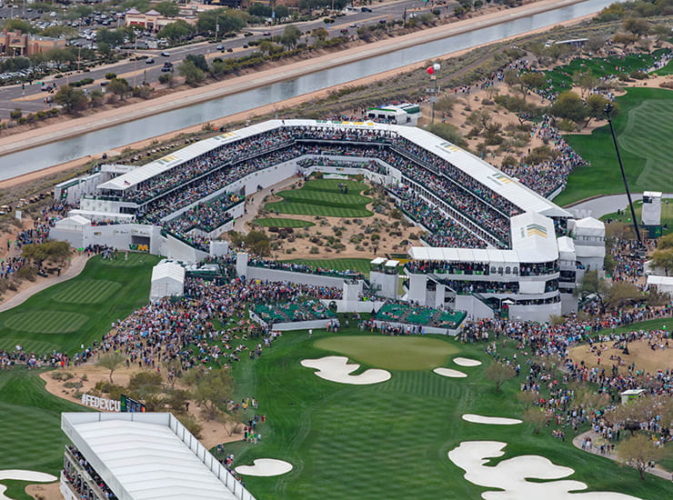 A crowds, in stadium seating, surround professional golfers on the 16th hole at the 2020 Waste Management Phoenix Open, Phoenix, AZ