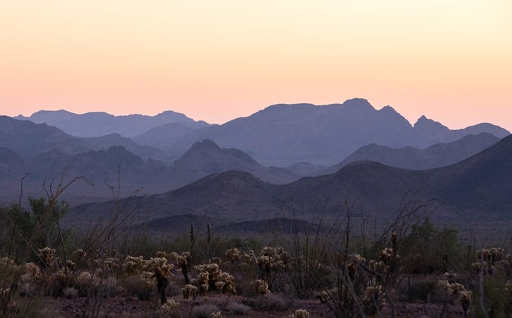 Purple mountain ranges under a yellow-orange sky