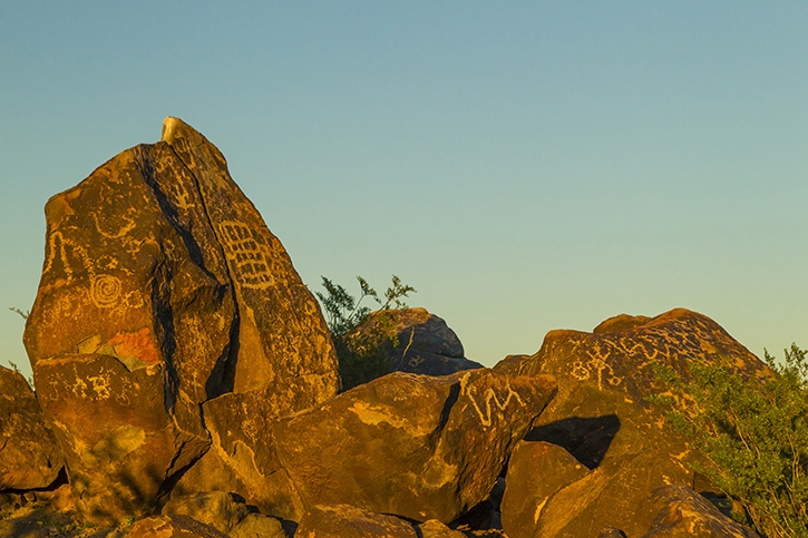 A boulder with petroglyphs during the day.
